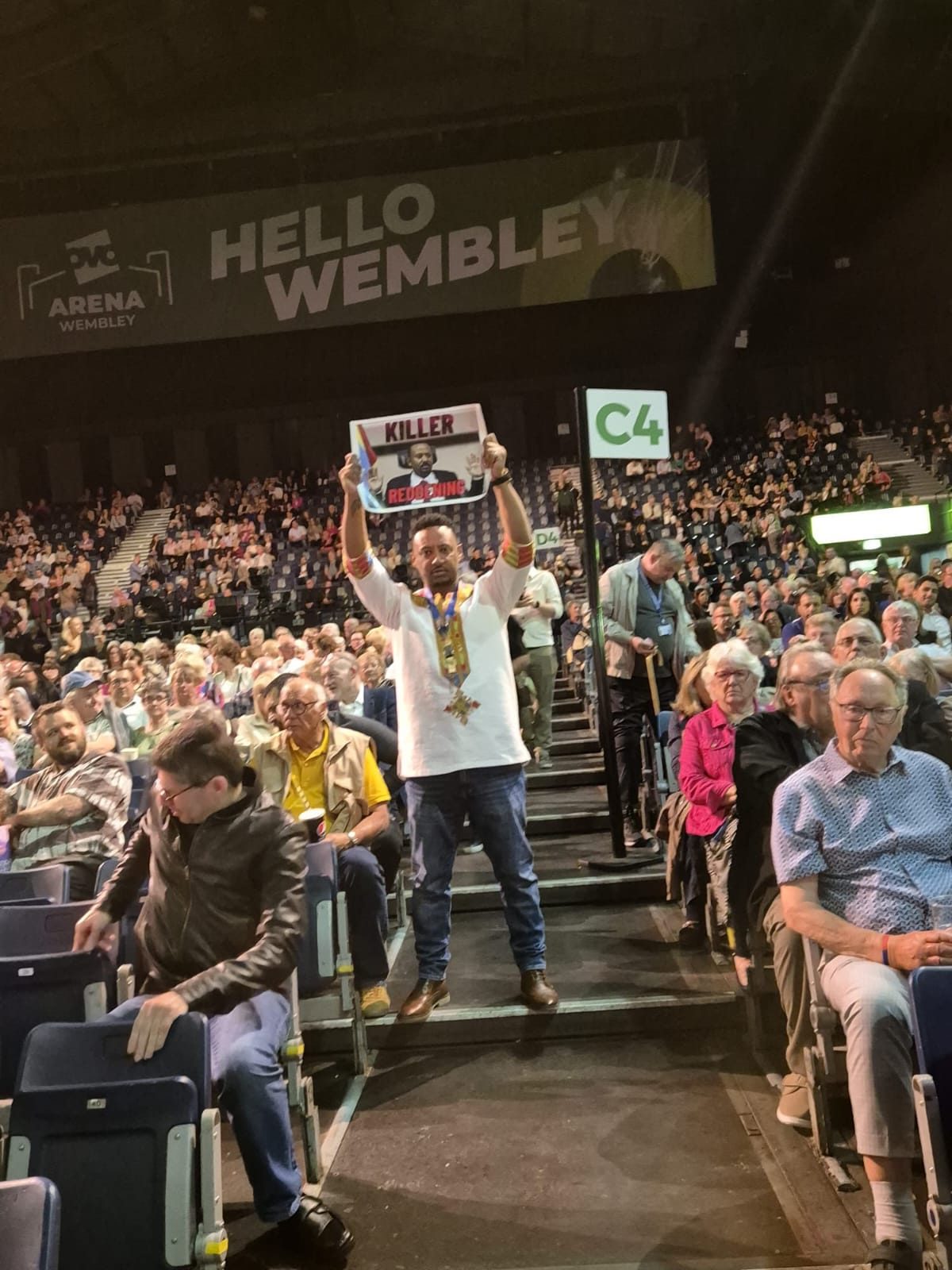 A London Fano campaigner standing in a crowded arena, holding a placard above his head